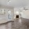 Spacious and well lit living room with wood flooring, large windows and open access to the kitchen
